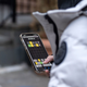 A person in a coat playing Wordle on a mobile phone.